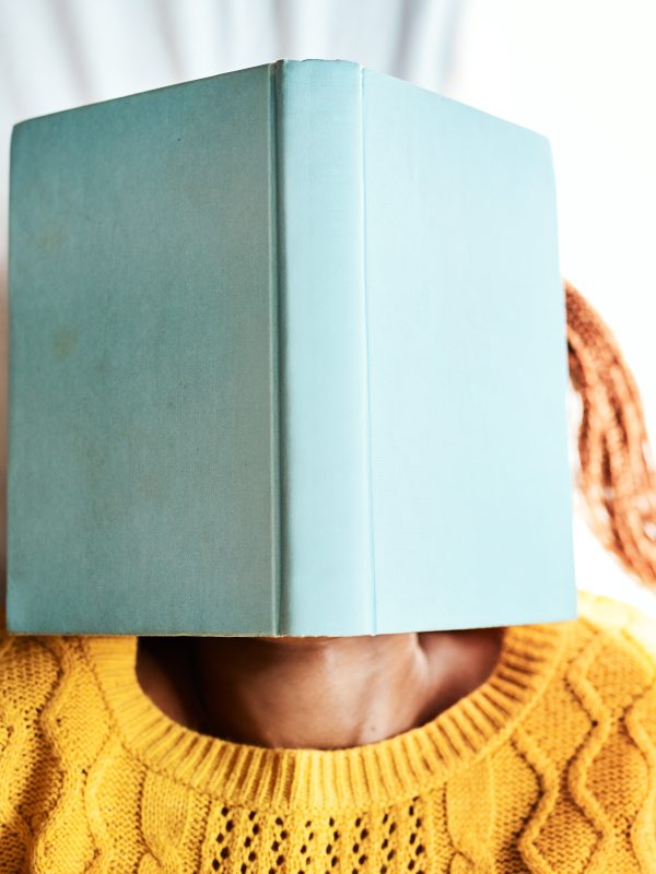 Shot of an unrecognizable woman lying with a book over her face.