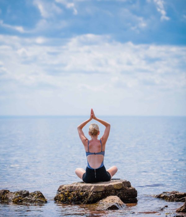 Young Woman doing Lotus Yoga Position in Front of the Ocean
